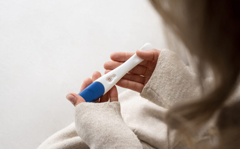 side-view-woman-holding-positive-pregnancy-test